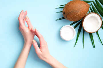 Female hands applying coconut moisturizer cream. Flat lay, top view. Natural organic cosmetic for...