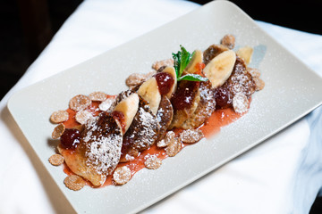 Juicy fritters with fruit for breakfast. Tasty cheesecakes with jam and bananas. Beautiful food from the restaurant cooked by a chef cook. Sweet dessert. A dish of flour and eggs.