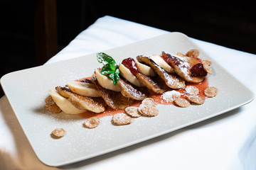 Juicy fritters with fruit for breakfast. Tasty cheesecakes with jam and bananas. Beautiful food from the restaurant cooked by a chef cook. Sweet dessert. A dish of flour and eggs.