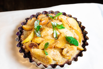 Juicy banana pie. Delicious Thanksgiving apple pie with mint or basil. Baking in the oven. Pie with banana. Sweet cupcake with baked fruit sprinkled with powder.