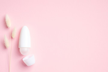 Blank roll-on deodorant bottle with dry flowers on pink background. Natural organic antiperspirant, sweat protection concept. Flat lay, top view