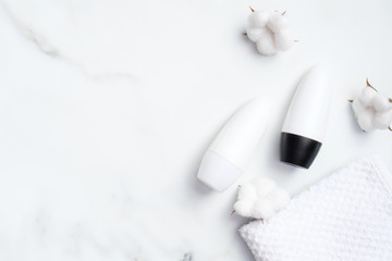 Roll-on deodorant with cotton flowers and towel on marble background. Antiperspirant packaging mockup, sweat protection concept. Flat lay, top view