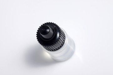 Close up shot of a transparent bottle with black cap that contain liquid on a white isolated background