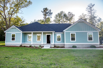 Front view of a brand new construction house with blue siding, a ranch style home with a yard - obrazy, fototapety, plakaty