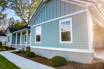 Front view of a brand new construction house with blue siding, a ranch style home with a yard