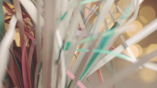 Close up of paper snippets rustling sound with defocused fairy lights in background. 4K resolution macro shot. Shallow depth of field. High quality audio recorded with condenser microphone.