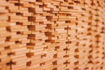 Closeup woodpile of lumber construction material at sawmill. Stack of wooden boards at wood production factory. Furniture, plywood manufacturing. Timber processing background. Small depth of field