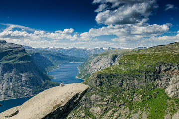 Trolltunga. Troll language in Norway. Rocky ledge above the fjord. Natural landmark of Norway. Girl sitting on the edge of a rocky cliff
