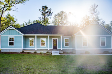 Front view of a brand new construction house with blue siding, a ranch style home with a yard and a...