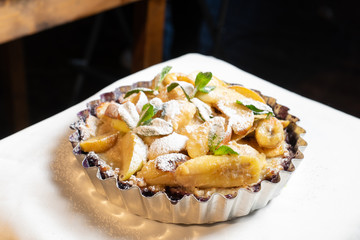 Juicy banana pie. Delicious Thanksgiving apple pie with mint or basil. Baking in the oven. Pie with banana. Sweet cupcake with baked fruit sprinkled with powder.