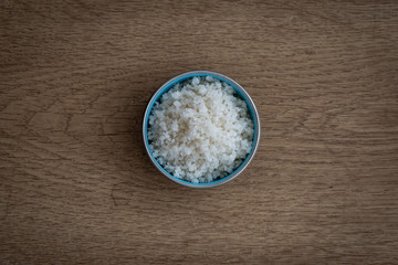 Grobes Meersalz in einer Schale auf Holztisch, aus der Vogelperspektive im Querformat.