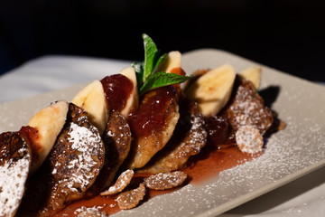 Juicy fritters with fruit for breakfast. Tasty cheesecakes with jam and bananas. Beautiful food from the restaurant cooked by a chef cook. Sweet dessert. A dish of flour and eggs.