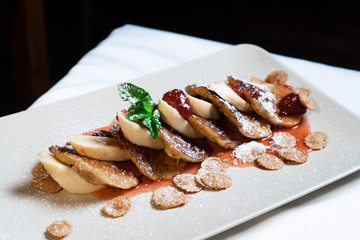 Juicy fritters with fruit for breakfast. Tasty cheesecakes with jam and bananas. Beautiful food from the restaurant cooked by a chef cook. Sweet dessert. A dish of flour and eggs.