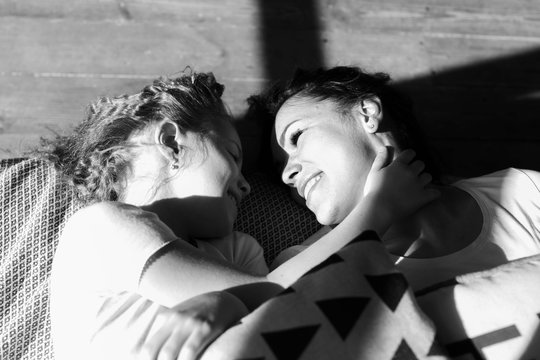 B&W photo. Young Happy Mother and Little Doughter Together. Beautiful Smiling Woman spending time with Cute Adorable Daughter. Mom and Child lying on Bed in Sunlight. Selective focus.