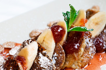 Juicy fritters with fruit for breakfast. Tasty cheesecakes with jam and bananas. Beautiful food from the restaurant cooked by a chef cook. Sweet dessert. A dish of flour and eggs.