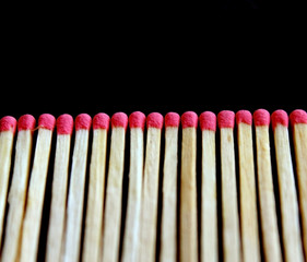 Row of aligned new fire matchsticks on black background