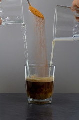 Coffee milk and water mix in small glass on stone desk