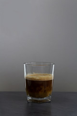 Milk mix in coffee in small glass on stone desk