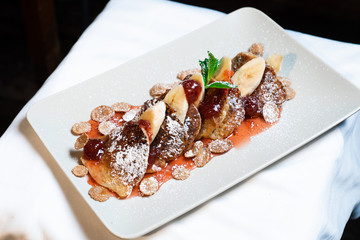 Juicy fritters with fruit for breakfast. Tasty cheesecakes with jam and bananas. Beautiful food from the restaurant cooked by a chef cook. Sweet dessert. A dish of flour and eggs.