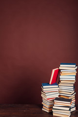 a lot of stacks of educational books to study at the college library on a brown background