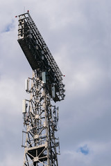 view of the tower for lighting stadiums, sports and concert areas, with searchlights and transmitting broadcasting antennas against a cloudy sky