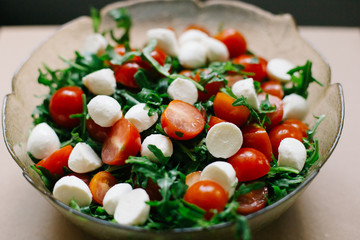 salad of fresh small tomatoes, arugula leaves and cheese