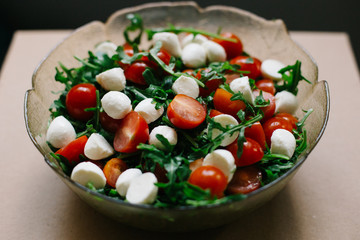 salad of fresh small tomatoes, arugula leaves and cheese