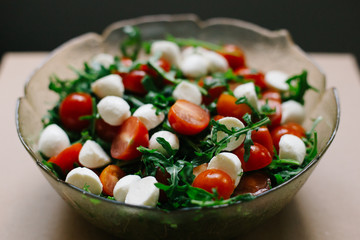 salad of fresh small tomatoes, arugula leaves and cheese