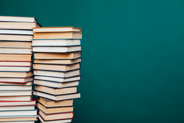 lots of stacks of educational books to teach in the school library on a green background