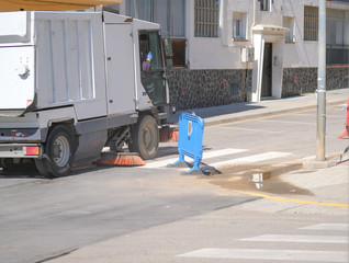 Sweeper truck industrial vehicle cleans urban streets of European city. Street cleaning machine at...