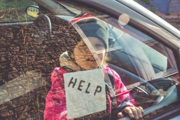 Obraz premium child in the car holds a note with the word help