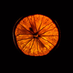 slice og mature orange fruit with backlight isolated on black background