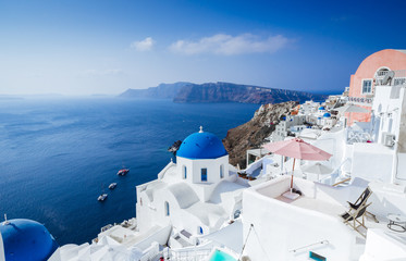 Panorama from Oia, blue domes of orthodox church and the caldera with boats in the back, Santorini...
