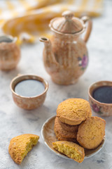 Homemade gluten-free cornmeal cookies on a light table, along with a coffee service and a yellow napkin in the background
