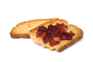 Closeup of strawberry jam on crackers slices on white background