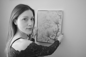 Portrait of a beautiful young woman looking us while she is stick a picture. Black and white.