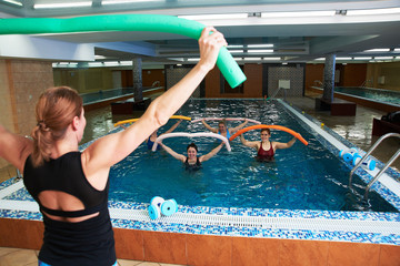 Young girls and adults women do aqua aerobics in a swimming pool with a trainer, fitness exercises for weight loss and wellness in water