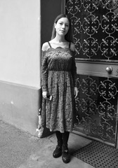 Full picture of a beautiful young woman with long hair and a lace dress, with an ancient wrought iron door in the background. Black and white.