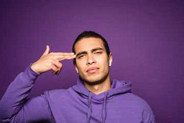 Bang! Brutal young muscular man showing gun gesture near his head. Threatening symbol. Gangster role