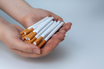 The girl holds a lot of loose cigarettes in her hands. White background