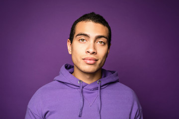 Headshot of sceptic self confident cheerful male. Smiling man. Posing in studio against purple background