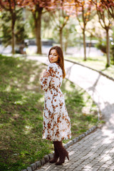 Beautiful young woman near the blooming spring tree. Attractive girl enjoying her time outside in park. Spring time.