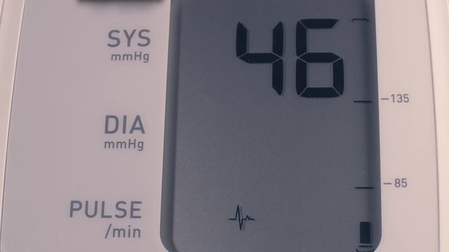 Blood pressure monitor close up. The device shows the result of blood pressure measurement on the display. It is showing symptoms of hypertension, increased blood pressure and increased heart rate