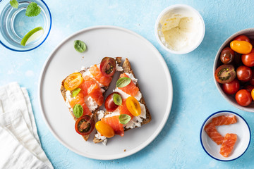 Delicious and tasty sandwich with salmon, basil, cherry tomatoes and caper. Close up selective focus. Traditional italian cuisine appetizer. Seafood. Food photo for menu or recipe. Top view flat lay