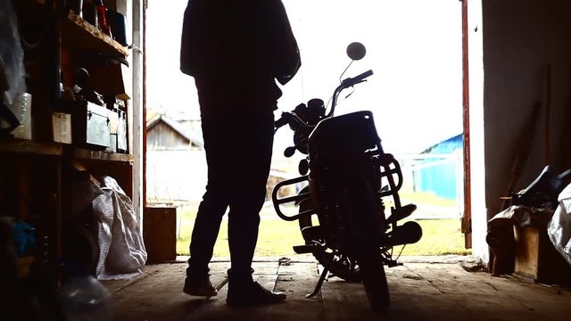 young man rides a motorcycle out of a garage