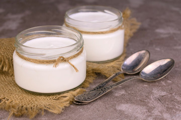 Two jars of organic sour cream on a gray background.