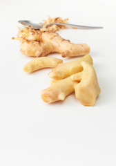 Cut and peeled young ginger root on a white background