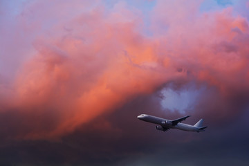 Commercial airplane flying through clouds in dramatic sunset light. Travel concept