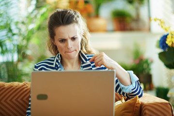 concerned trendy woman with laptop at modern home in sunny day