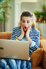 shocked modern female with laptop in modern house in sunny day